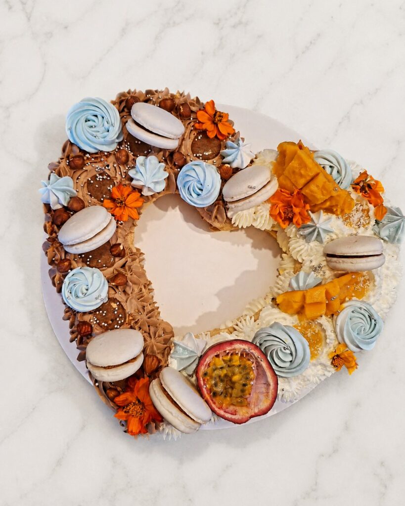 Number cake en forme de cœur, moitié chocolat-noisette et moitié mangue-passion, décoré de macarons et de fleurs