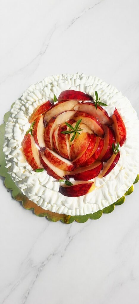 Charlotte aux pêches décorée de fruits frais et de crème