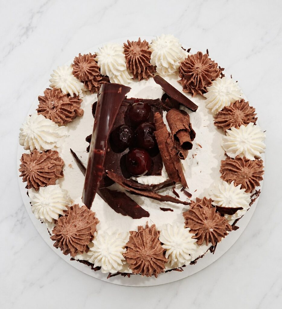 Vue du dessus d’une forêt-noire décorée de crème, de chocolat et de cerises