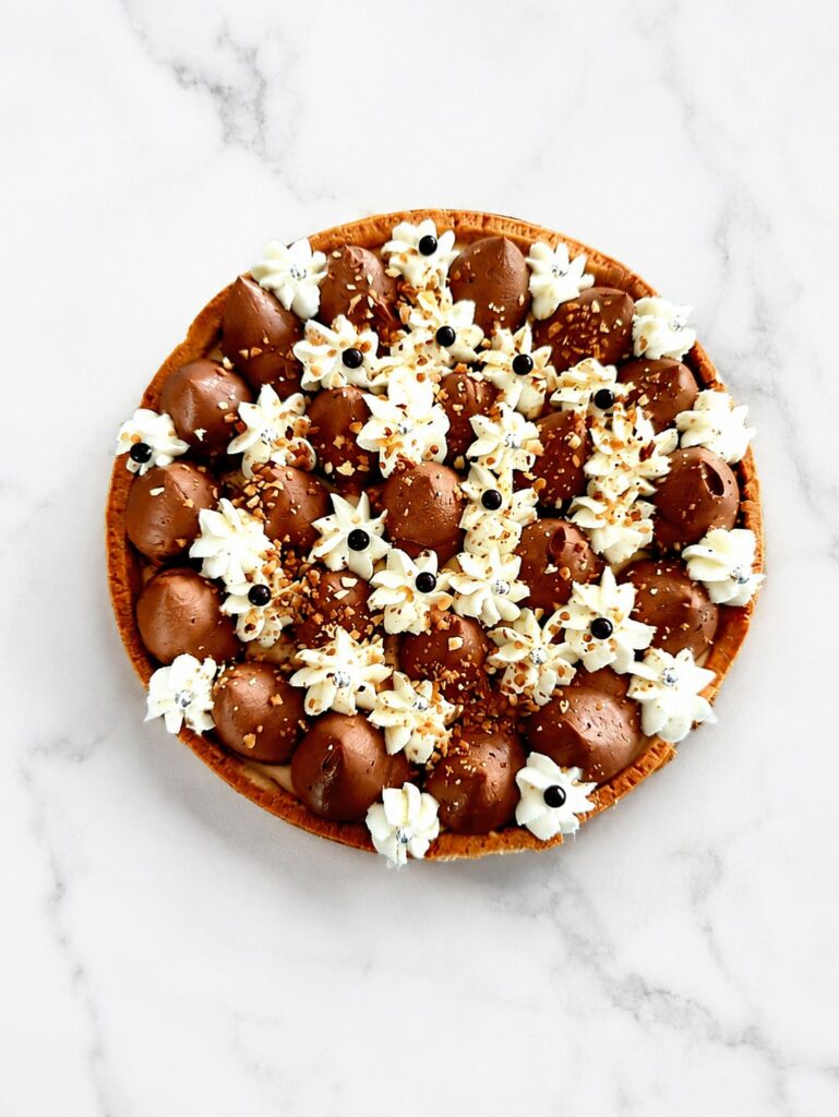 Tarte au chocolat et à la noisette décorée de crèmes pochées